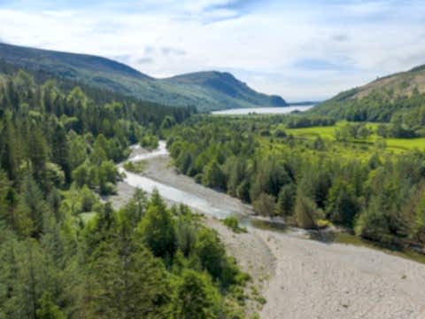 Drone photo of a river running through pine trees towards a lake at Wild Ennerdale.