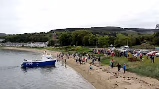 People on the beach at a boat launch.