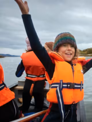 Seawilding volunteers in orange life vests releasing oysters from a boat