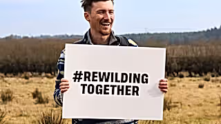 Man holding rewilding together sign