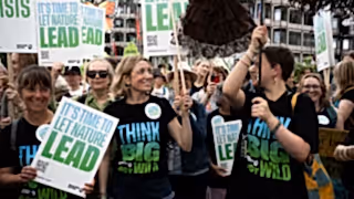 A group of people with signs protesting in the street for nature